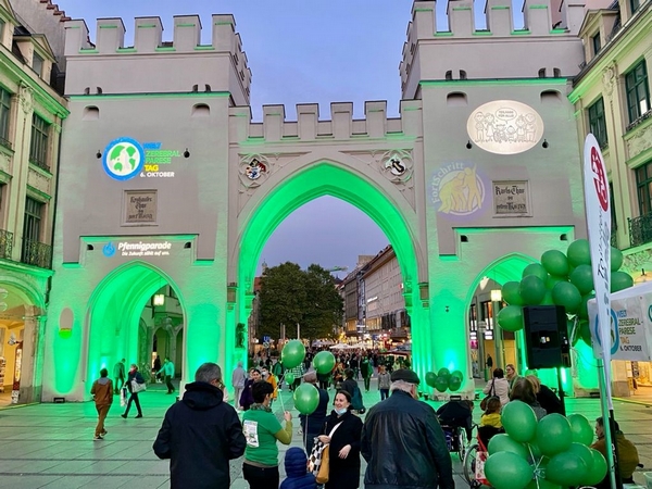 Grün erleuchtetes Karlstor in München mit Logos am Welt-Zerebralparese-Tag